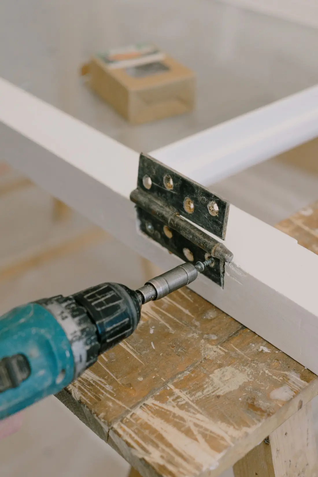 Cordless drill fixing a hinge to a white door frame
